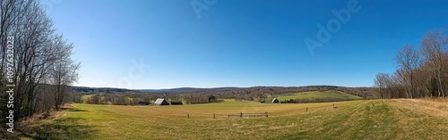 Rolling hills under a clear blue sky with lush green fields and early spring vegetation in a serene rural landscape