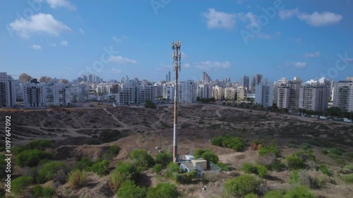 Parallax around a modern cellular antenna in an urban area on sandy ground close to residential buildings on the outskirts of the city