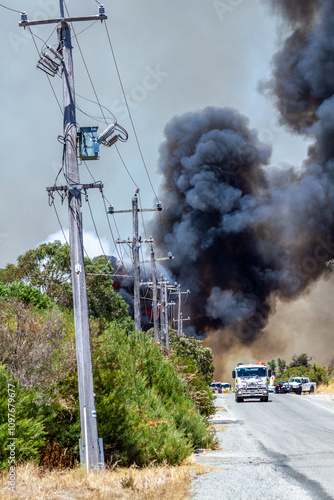 Bushfire with thick black smoke and emergency vehicles photo