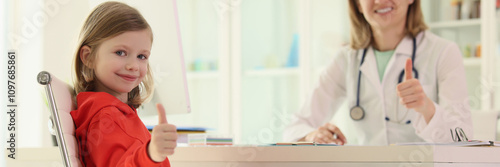 Little girl and doctor show sign of approval at appointment photo