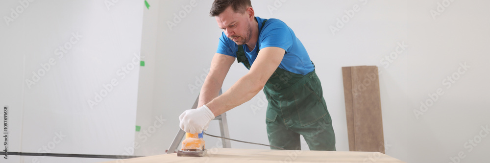 Focused carpenter polishes wooden board surface in room