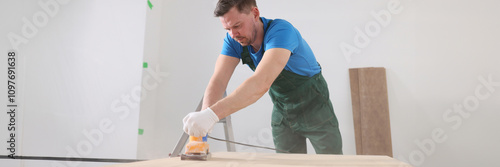 Obraz na płótnie Focused carpenter polishes wooden board surface in room w salonie