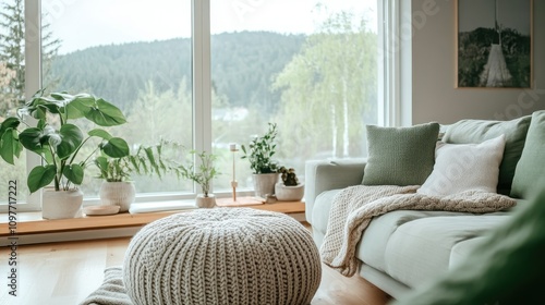 A serene Scandinavian-inspired living room with soft greens and grays, minimal decor, and a cozy knit pouf near a large picture window