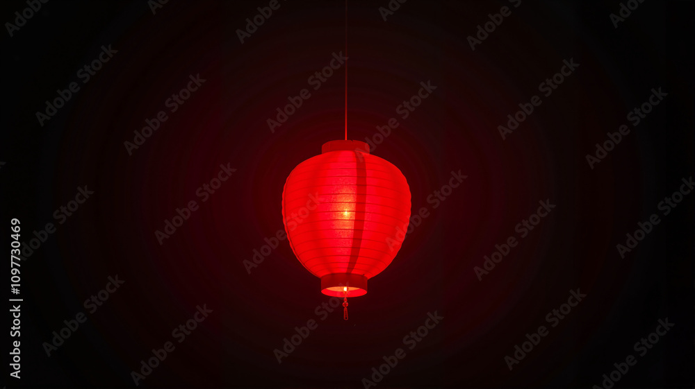 Obraz premium Single glowing red lantern against dark background