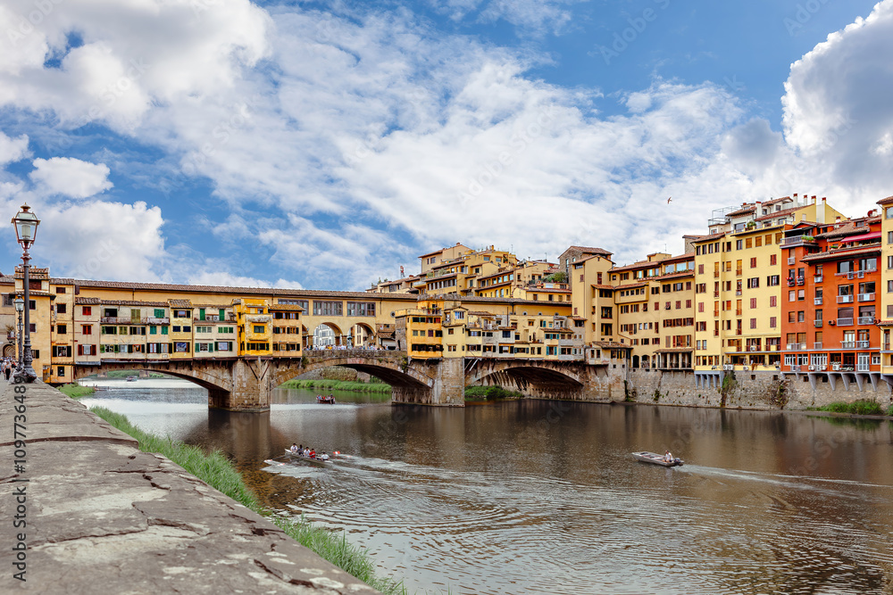 Arno River. Iconic Ponte Vecchio Bridge framed by colorful buildings and a beautiful sky in Florence.