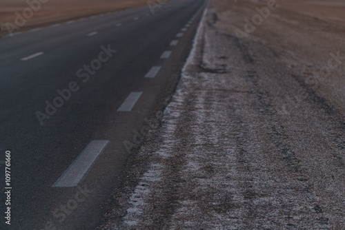 an asphalt road leading through a flat section of desert