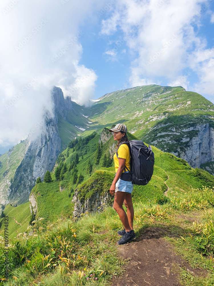Obraz premium Hiking through majestic mountain on a sunny day with lush greenery and dramatic clouds in Swiss Alsp