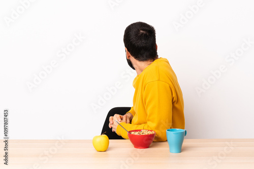 Caucasian man having breakfast in a table in back position and looking side. photo