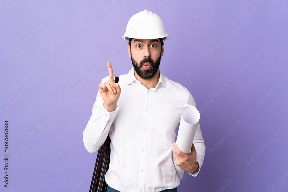 Young architect man with helmet and holding blueprints over isolated purple background intending to realizes the solution while lifting a finger up Young architect man with helmet and holding blueprints over isolated purple background intending to realizes the solution while lifting a finger up