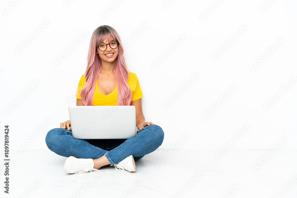 Young mixed race woman with a laptop with pink hair sitting on the floor isolated on white background posing with arms at hip and smiling Young mixed race woman with a laptop with pink hair sitting on the floor isolated on white background posing with arms at hip and smiling