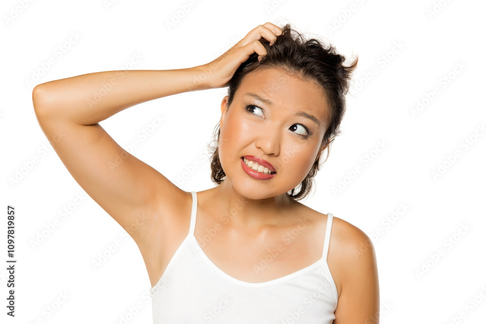 Beautiful nervous Asian girl with itch on her scalp on white background. Beautiful nervous Asian girl with itch on her scalp on white background.