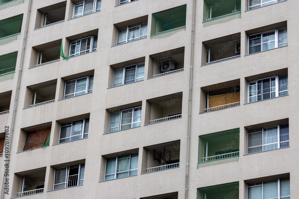 A close-up of a residential apartment building facade. The repeating square balconies and windows create a rhythmic architectural pattern. A close-up of a residential apartment building facade. The repeating square balconies and windows create a rhythmic architectural pattern.