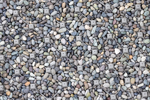 Wallpaper Mural A detailed close-up view of gray and multicolored gravel interspersed with metallic anchors embedded into the ground. This textured composition captures an intriguing mix of natural stones. Torontodigital.ca