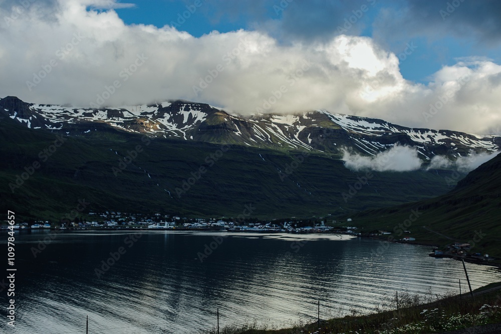 Obraz premium Coastal town beneath snow-capped mountains