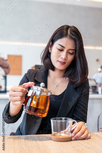 A beautiful woman in a black suit was pouring tea into a cup.