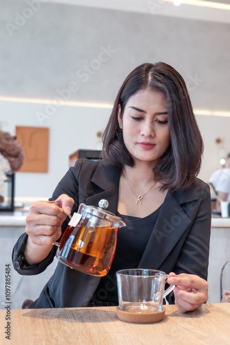 A beautiful woman in a black suit was pouring tea into a cup.