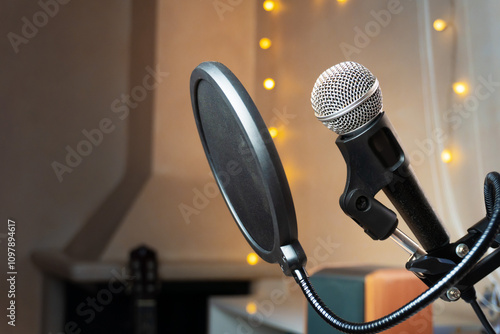 A microphone with a pop filter is stending on a beige background with fairy lights photo