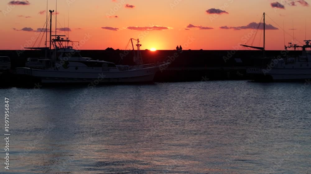 西伊豆の漁港と夕陽 それを眺めるカップル ドローン 西伊豆の漁港と夕陽 それを眺めるカップル ドローン