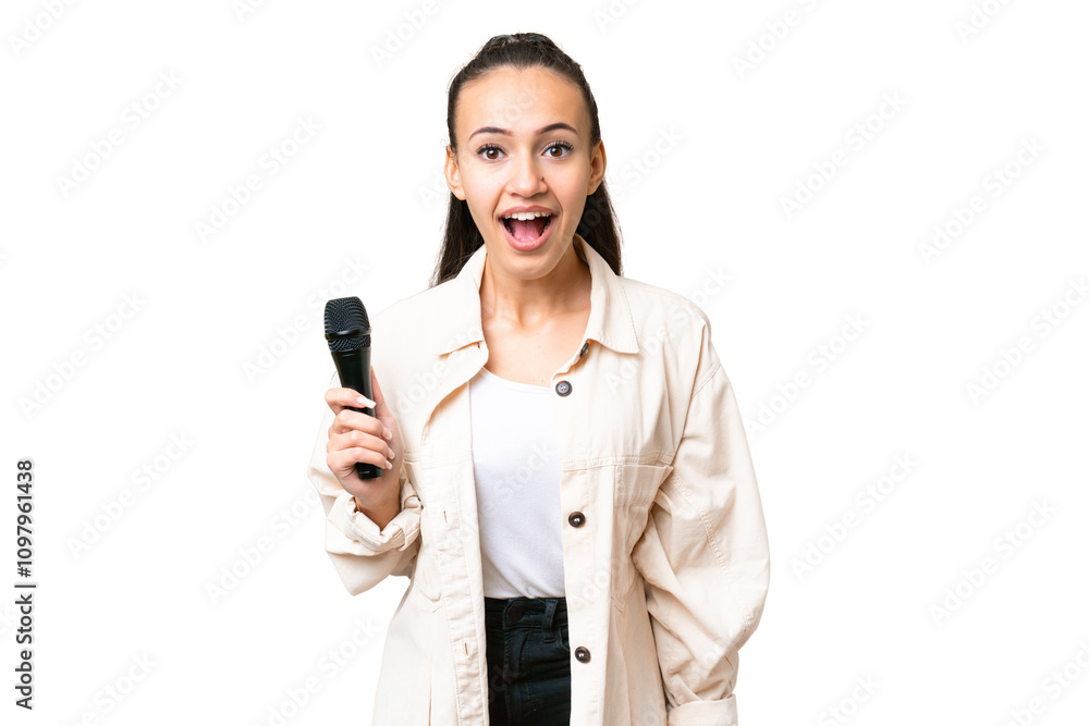 Young singer woman picking up a microphone over isolated chroma key background with surprise facial expression Young singer woman picking up a microphone over isolated chroma key background with surprise facial expression