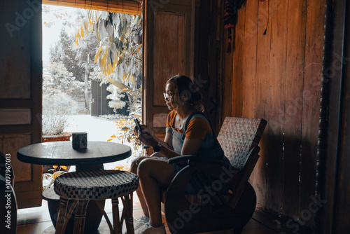 A woman is sitting in her living room, furnished in the old-fashioned style of a Javanese village. photo