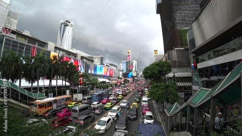 BANGKOK, THAILAND - AUGUST 2024 : Aerial high angle view of busy traffic around downtown shopping area in daytime. Transportation and street traffic concept video.