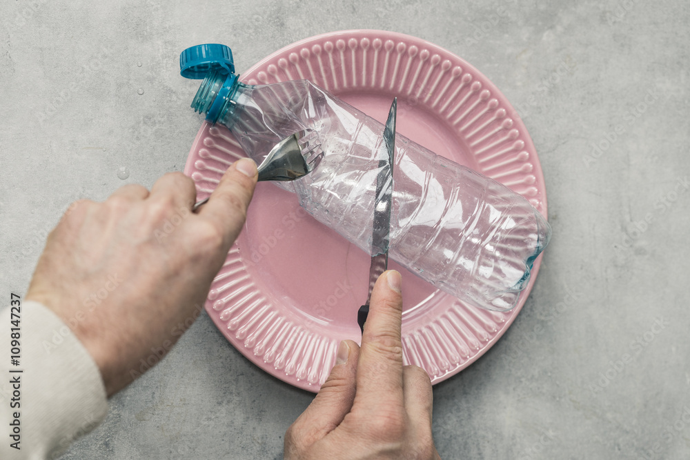 Microplastic in food, Concept, Global environmental problem, Plastic PET bottle on a plate, Hands cutting plastic with a knife and fork microplastics and pollution entering the body, closeup