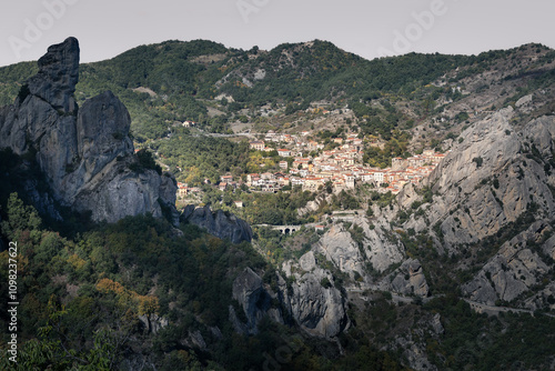 Italian village on hill side surrounded by trees and rocky mountains, sunny day, Castelmezzano, Italy