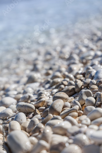 Pebbles close up on sea beach on sunny day with blurred background and foreground