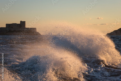 Sea wave in the rays of the setting sun against the backdrop of the Chateau d'If