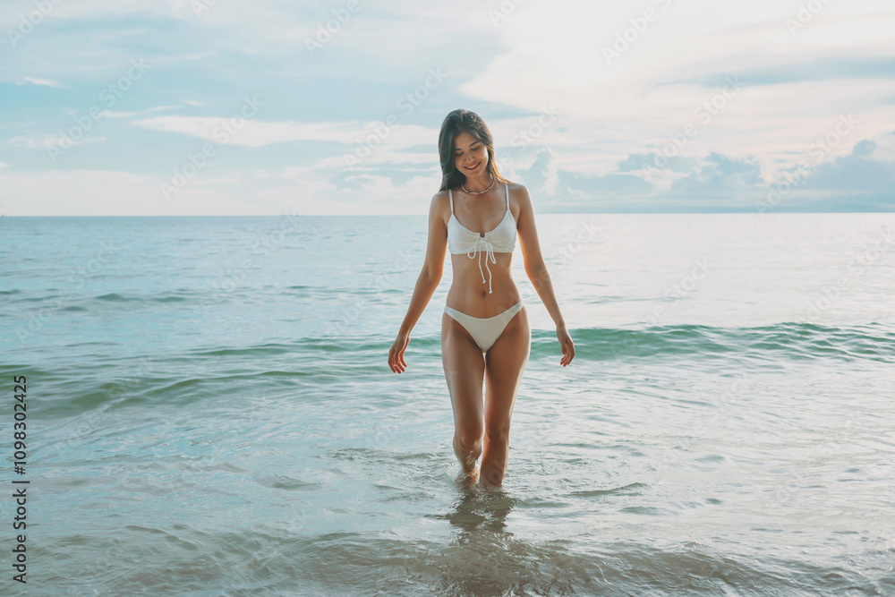 Fototapeta premium woman is walking in the ocean wearing a white bikini