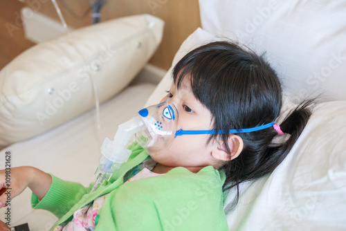 Sick little asian girl inhalation with nebulizer for respiratory treatment photo