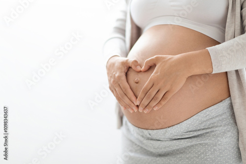 Fotografi Cropped shot of pregnant woman in homewear holding hands in heart-shaped symbol