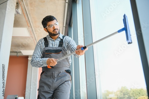 Male professional cleaning service worker cleans the windows and shop windows of a store with special equipment photo