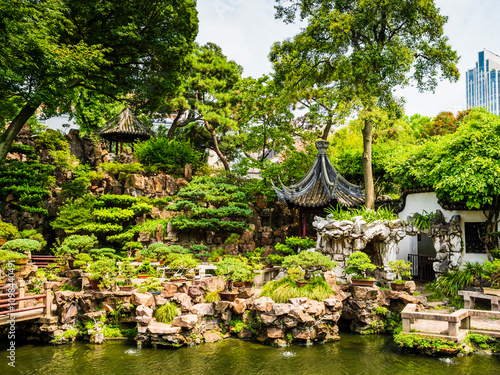 Stunning view of Yuyuan garden and one of its peaceful pond with traditional chinese architecture, lush greenery and rock formations, Shanghai, China
