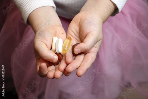 Child holding various pills and supplements in palms.