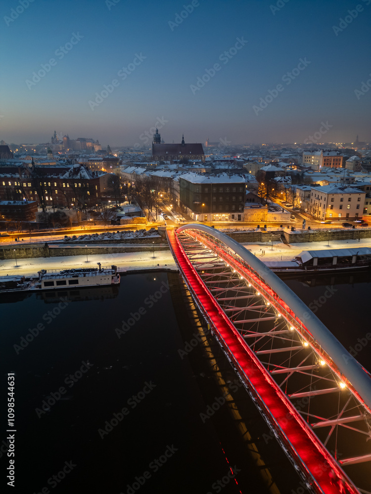 Fototapeta premium Bernatka footbridge over Vistula river in Krakow, Poland, illuminated in the winter evening