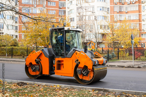 Compacting a new layer of asphalt with a roller. A vibratory roller is used in road construction. photo