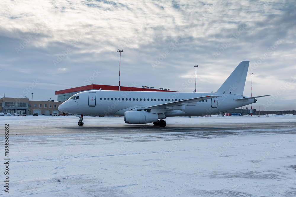 Fototapeta premium White passenger aircraft taxiing on the airport at winter
