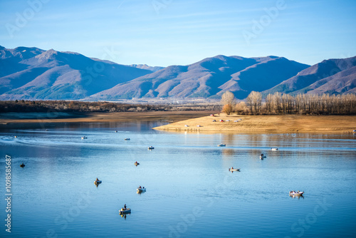Lots of fishing boats in a dam with a mountains in the background