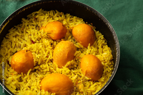 Quadro su tela Uma panela preta cheia de arroz com pequi, uma comida típica brasileira, sobre um forro verde