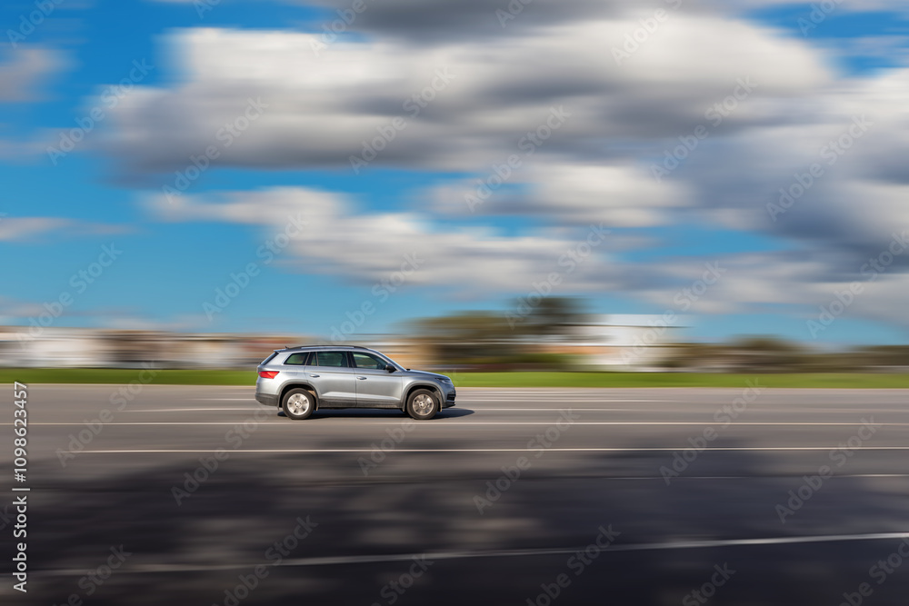 Naklejka premium Dynamic running car on road. A gray SUV driving with a blurred background at speed