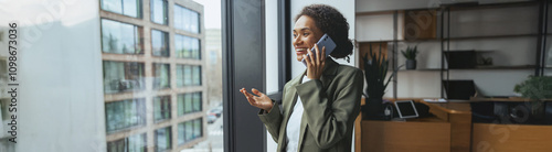 a woman is standing in front of a window talking on a cell phone