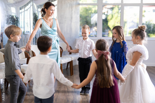 Joyful schoolboys and schoolgirls of primary classes having merry roundelay in events salon photo