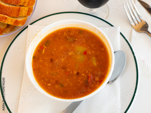 Portion of tratitional Spanish lentil soup with chorizo, sopa de lentejas, served on table. photo