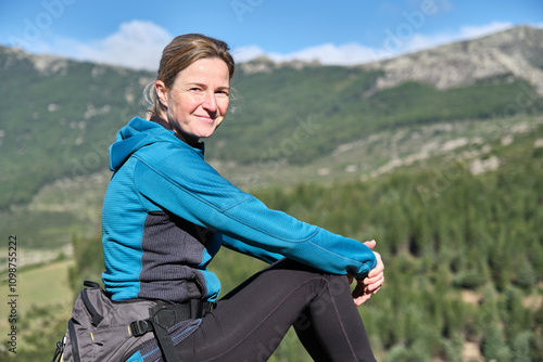 Portrait of a woman sitting on the mountain looking at the camera.