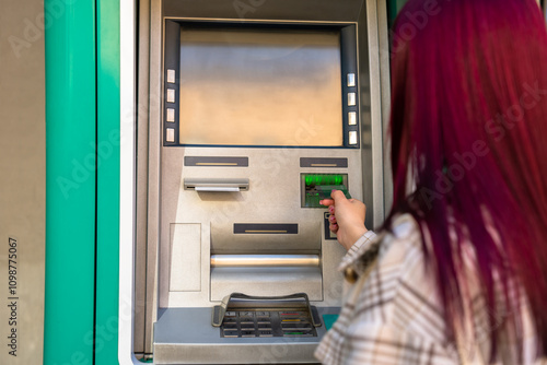 Woman with card, using ATM photo