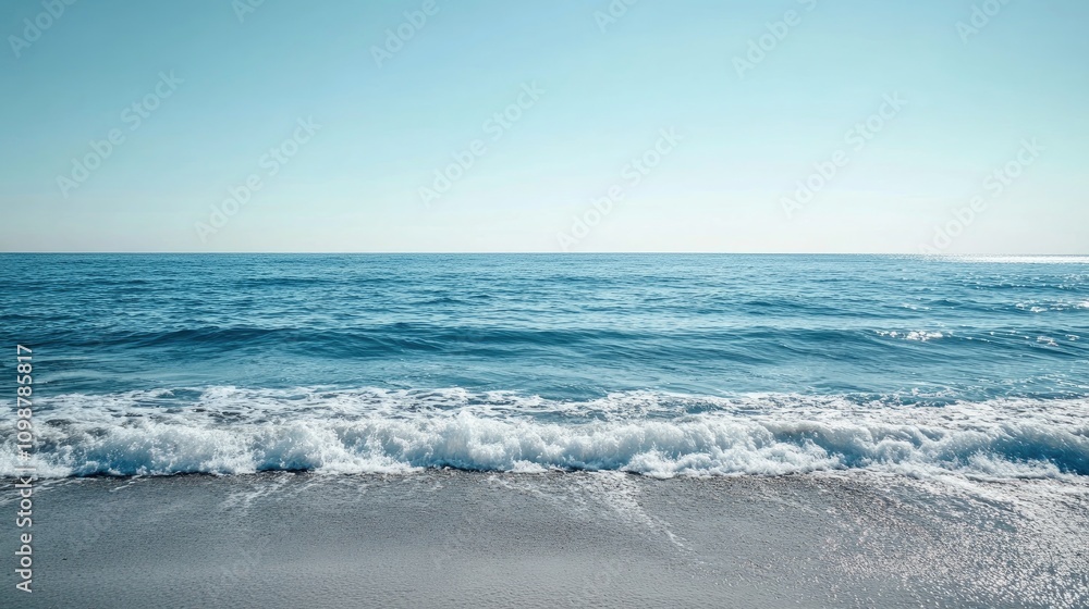 Fototapeta premium Serene Ocean Horizon with Gentle Blue Waves Lapping Against a Sandy Shore Under a Bright Clear Sky