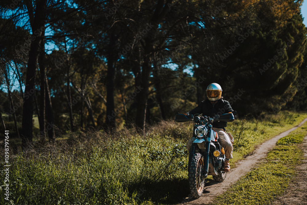 Hombre con barba y estilo alternativo con moto de campo en paso de bosque