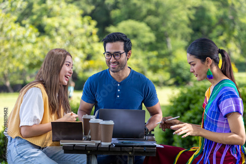 Group of diversity college student is meeting and working on thesis and project outside in the university campus garden during summer. photo