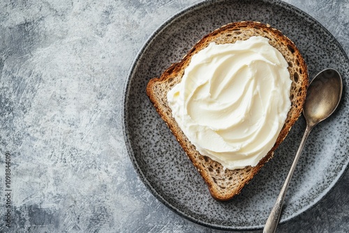 Top view of oat wholegrain bread with swirls of ricotta mascarpone Philadelphia or cream cheese Grey background plate and space available photo